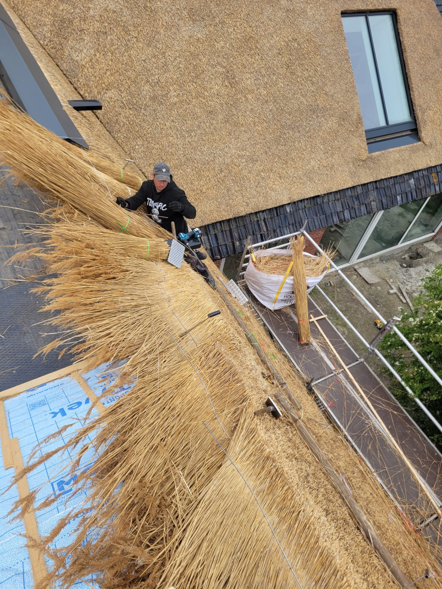 Rietdekker die riet aanbrengt op de dakvlakken